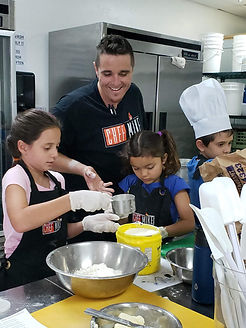 Chef Mike teaching young kids how to bake.