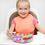Thumbnail: Smiling girl eating from colorful plate; wearing bib at the high chair
