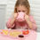 Thumbnail: Young girl drinks from pink cup at table with food and snacks