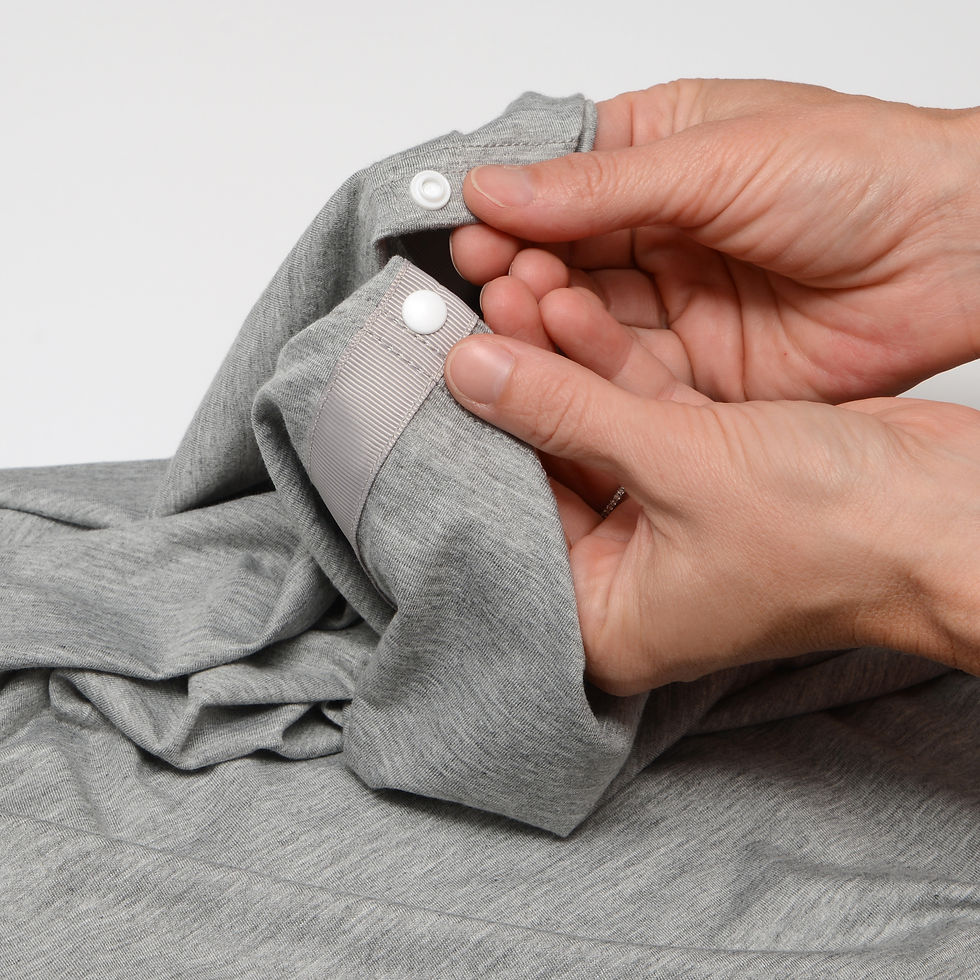 Thumbnail: Hands buttoning grey fabric, close-up with focus on the detail and texture.