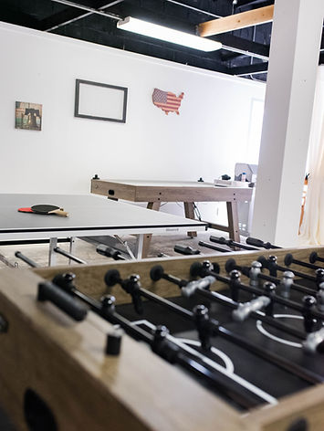 The room is equipped with multiple recreational tables, including a foosball table in the