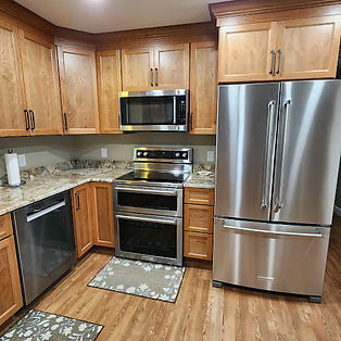 a kitchen featuring: Cabinetry: Medium-wood tone cabinets with dark hardware. Countertops