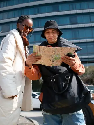 Two tourists standing outdoors checking a city map in front of a modern building