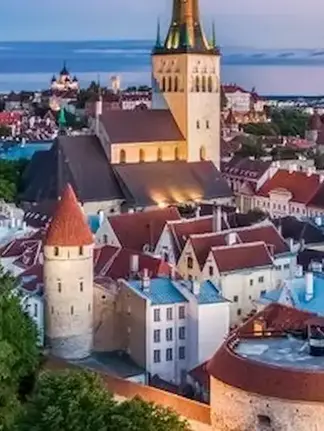 En panoramautsikt over Tallinn med gamle bygninger og kirketårn under en himmel i skumringen.