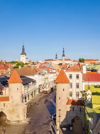 Panoramautsikt over Tallinn med fargerike bygninger og kirketårn under en skyfri himmel.