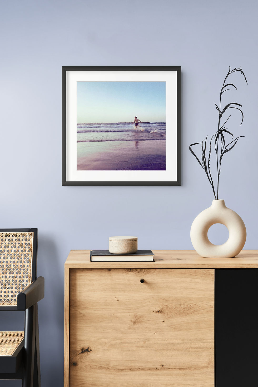 Framed ocean print above a wooden sideboard