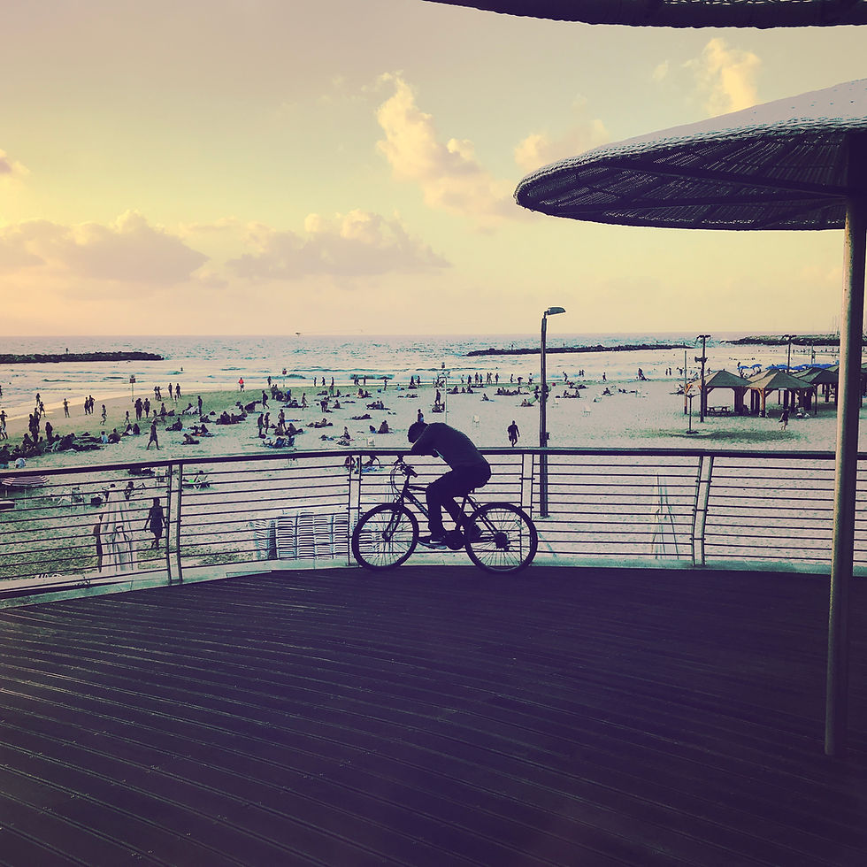 Cyclist on Bugrashov Beach boardwalk at sunset