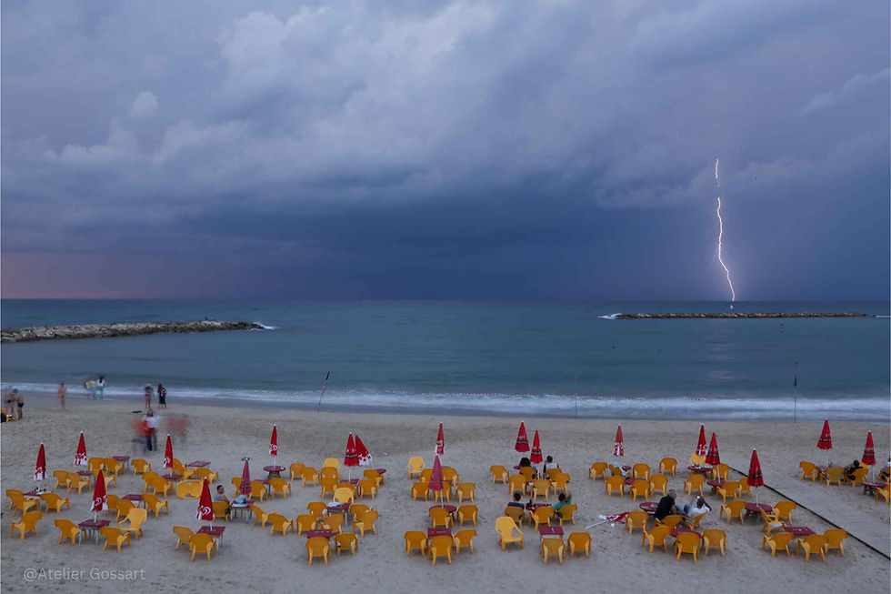 Lightning striking over the ocean at a beach resort.