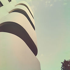 Modern white building with curved balconies against the sky