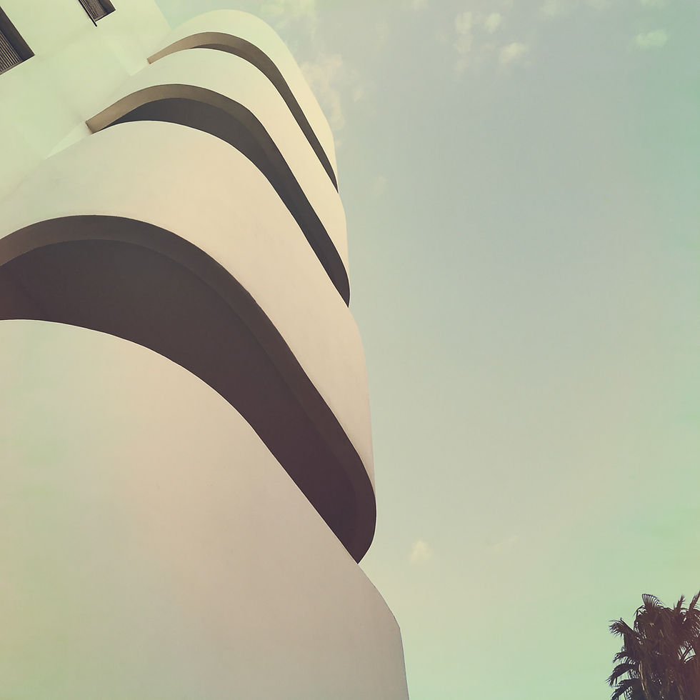 Curved balconies of a white Bauhaus building against the sky.