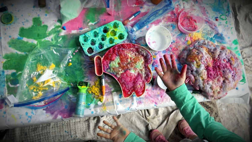 Toddlers hands showing red paint from mixing up materials with coloured magic powder paint jelly shaving cream and who knows what other sensory materials during an indoor messy play for things to do in byron bay for kids session at Lemontree Kids in Byron Bay.