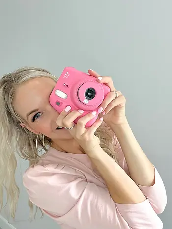 Danielle Van Velzer holding a pink camera capturing before and after skincare results in London Ontario
