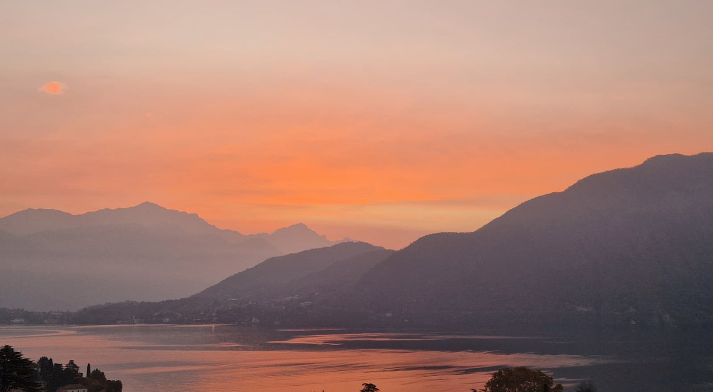 Sunrise over Lake Como from Tremezzina with golden light reflecting on the water and mountains in the distance