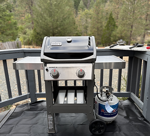 Grilling station at Trinity River Farmhouse with a propane BBQ, surrounded by mountain and river views.