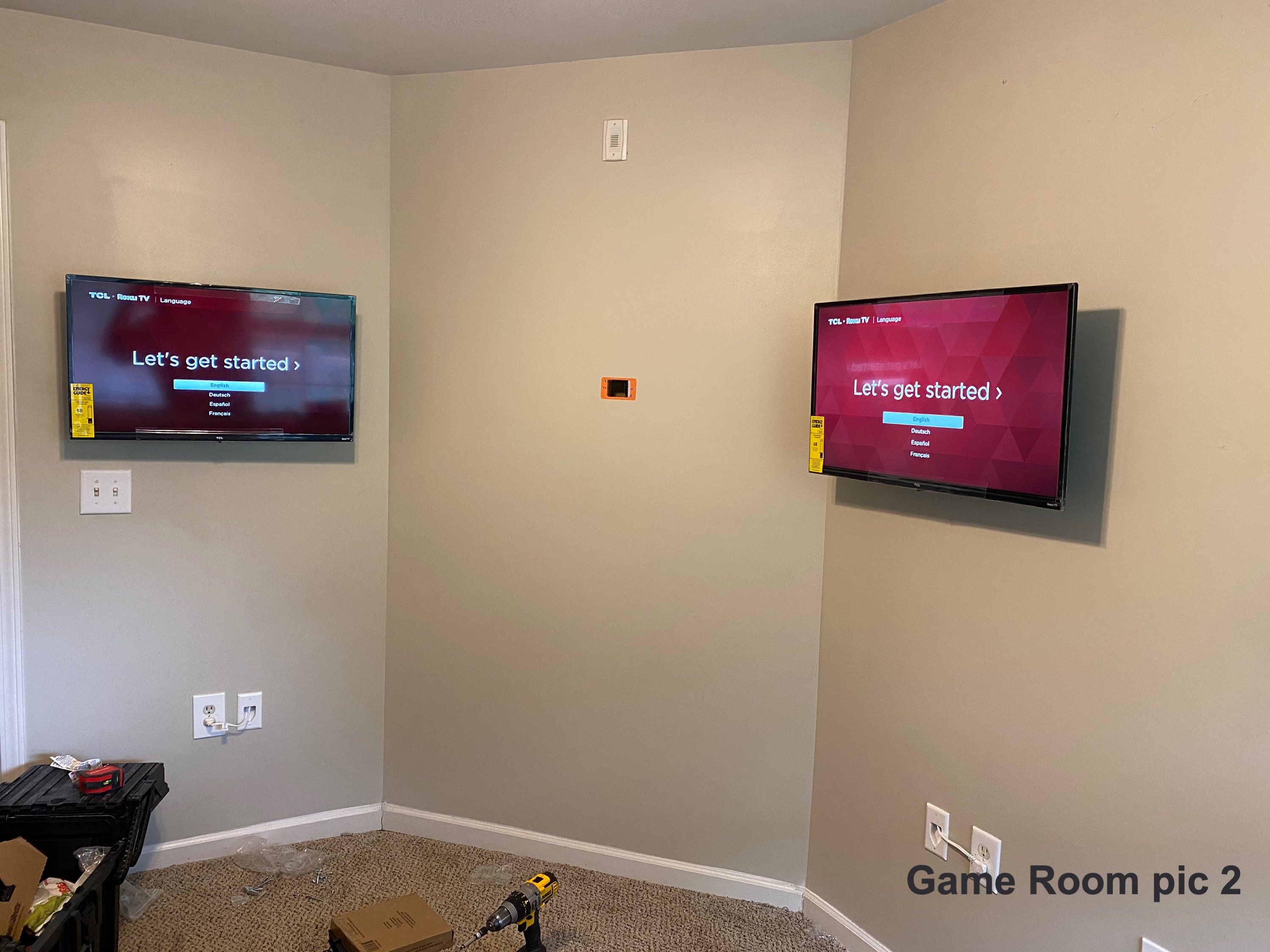 Two TVs mounted in adjoining corners of a game room