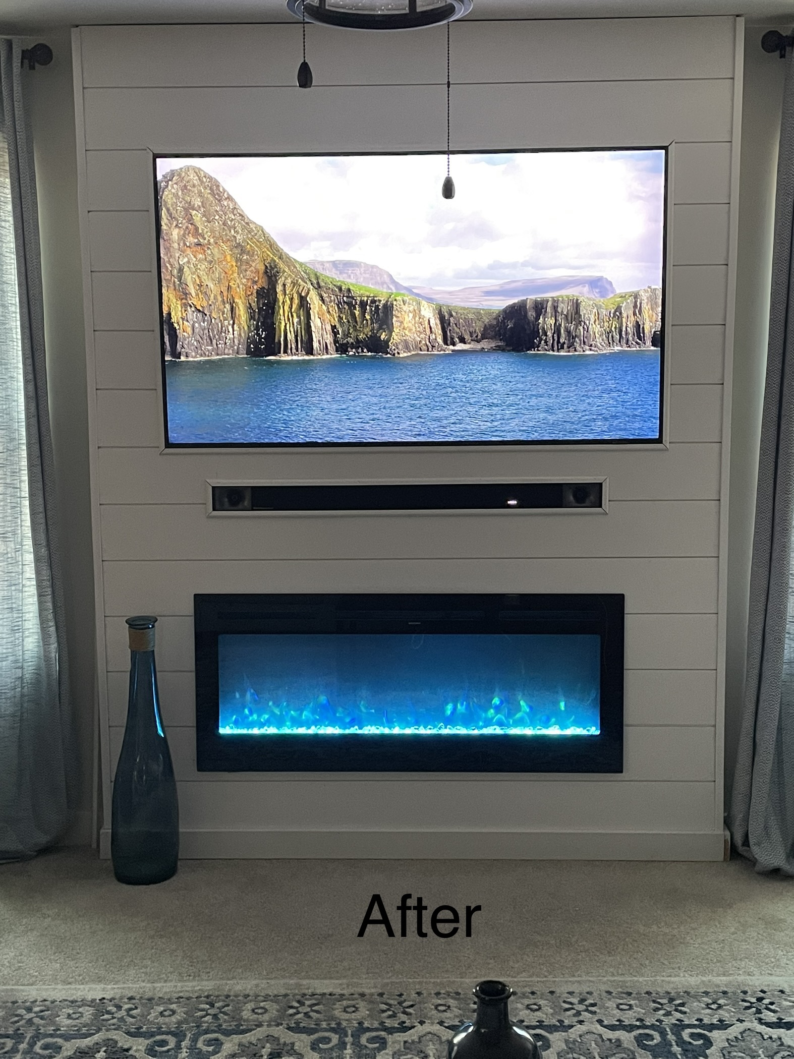 TV mounted above an electric fireplace on a shiplap accent wall with soundbar