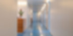 Hospital hallway with a blue floor and white walls.