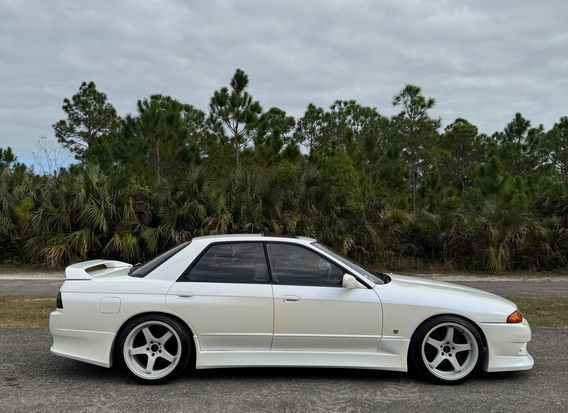 1990 Nissan Skyline GTS-4 Turbo for sale, featuring a sleek silver exterior, iconic boxy design, and distinctive turbocharged engine. The car is equipped with all-wheel drive, classic alloy wheels, and sports seats, showcasing the vehicle's blend of performance and style. Available for purchase, this model is a rare find for car enthusiasts.