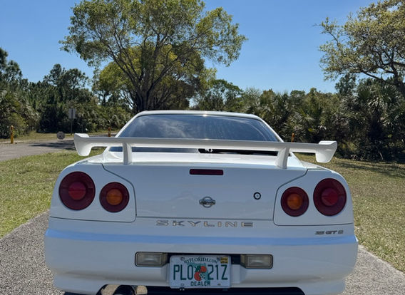Rear angle of the Nissan Skyline R34 GTT highlighting its aggressive stance and upgraded HKS exhaust system.