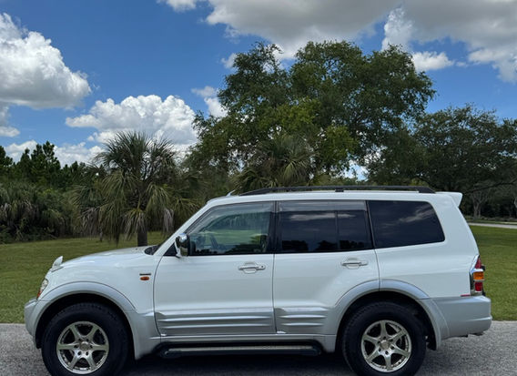 Right-hand drive 1999 Mitsubishi Pajero Long Exceed 4WD for sale by JDM Importer Lion JDM Imports LLC – side view of a rugged, silver SUV, showcasing its 4WD capabilities, spacious design, and well-maintained exterior, perfect for JDM car enthusiasts.