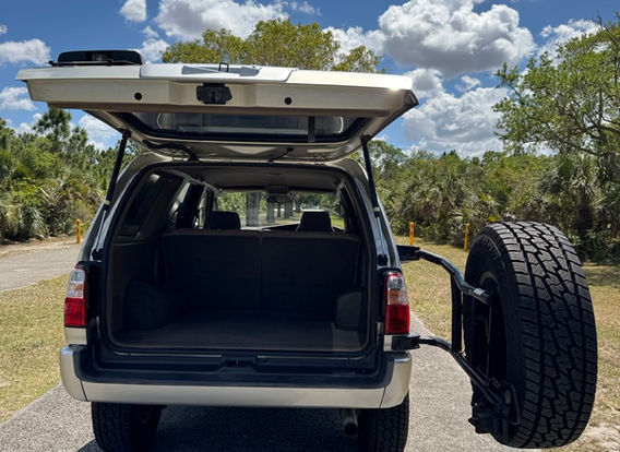 Rear view of the 1999 Toyota Hilux Surf with upgraded tail lights and a rugged off-road stance in Millennium Silver.