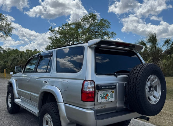 Rear view of the 1999 Toyota Hilux Surf with upgraded tail lights and a rugged off-road stance in Millennium Silver.