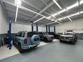 Vehicles positioned between YS 7702 Plus hoists in a workshop