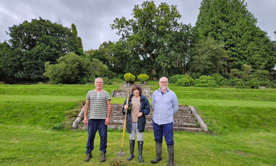 Three volunteers posing for a photograph on the lawn of the south terrace