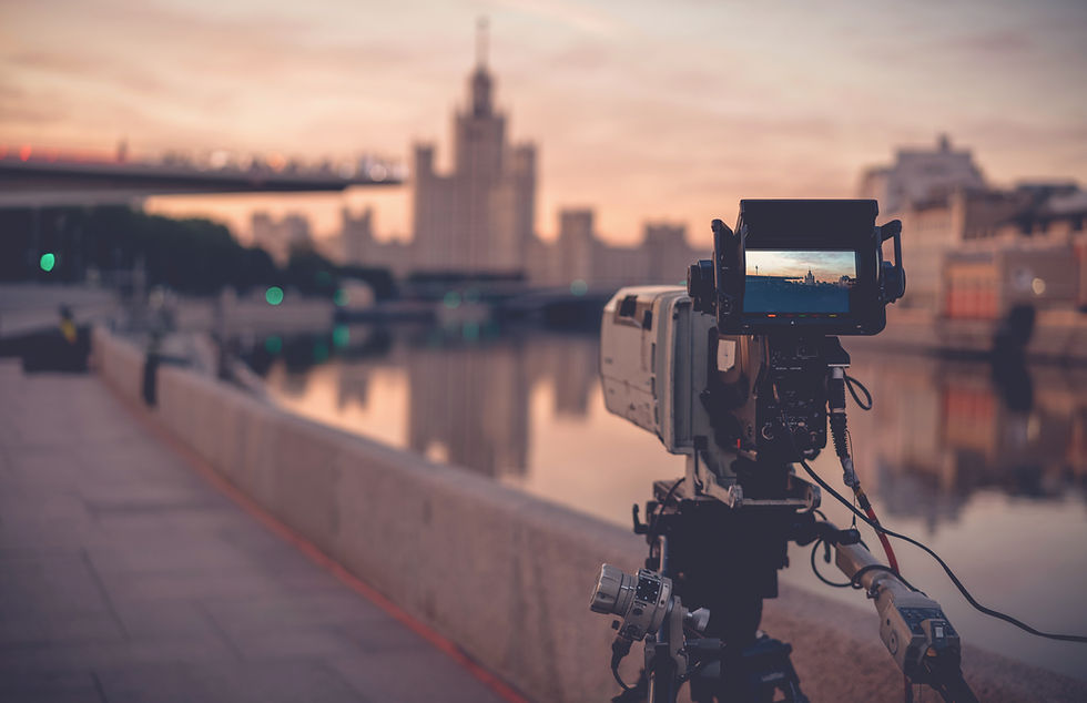 Videokamera auf Stativ vor Stadtkulisse bei Sonnenuntergang