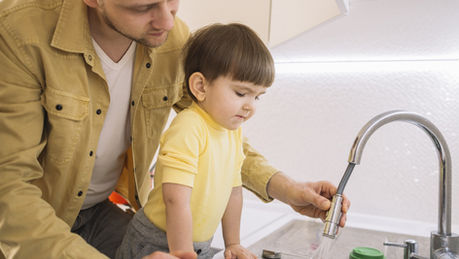 Father and son using a faucet