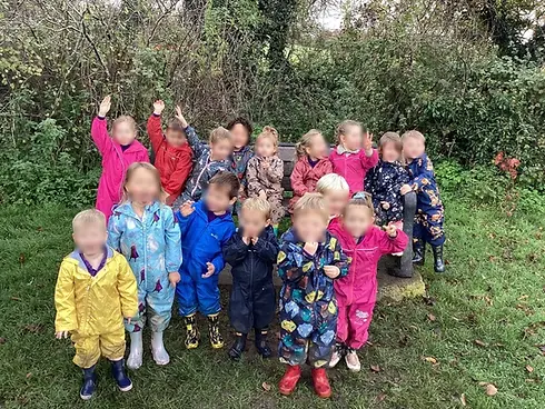 Group of young preschool children wearing colourful puddlesuits smiling outdoors together