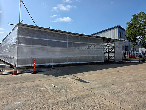 Building under construction wrapped in translucent plastic with scaffolding