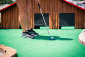 Person playing mini golf near barn