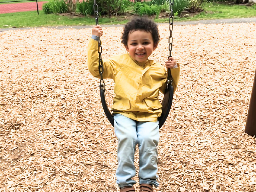 Smiling child enjoying a swing at a Rhode Island playground.