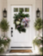 White front door with a green wreath and potted plants