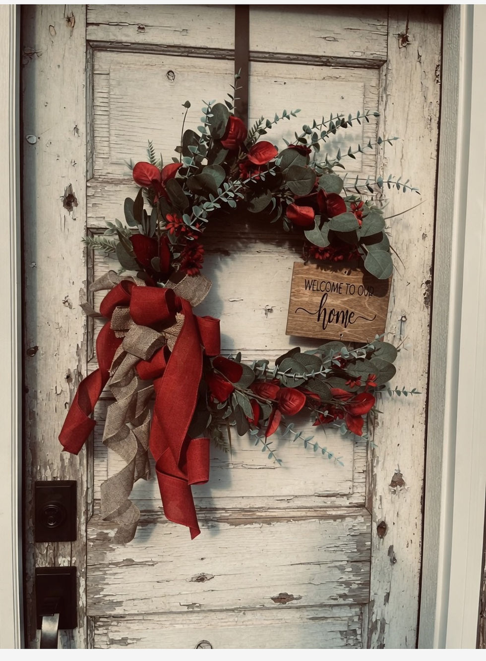 Festive red and green wreath on a white rustic door