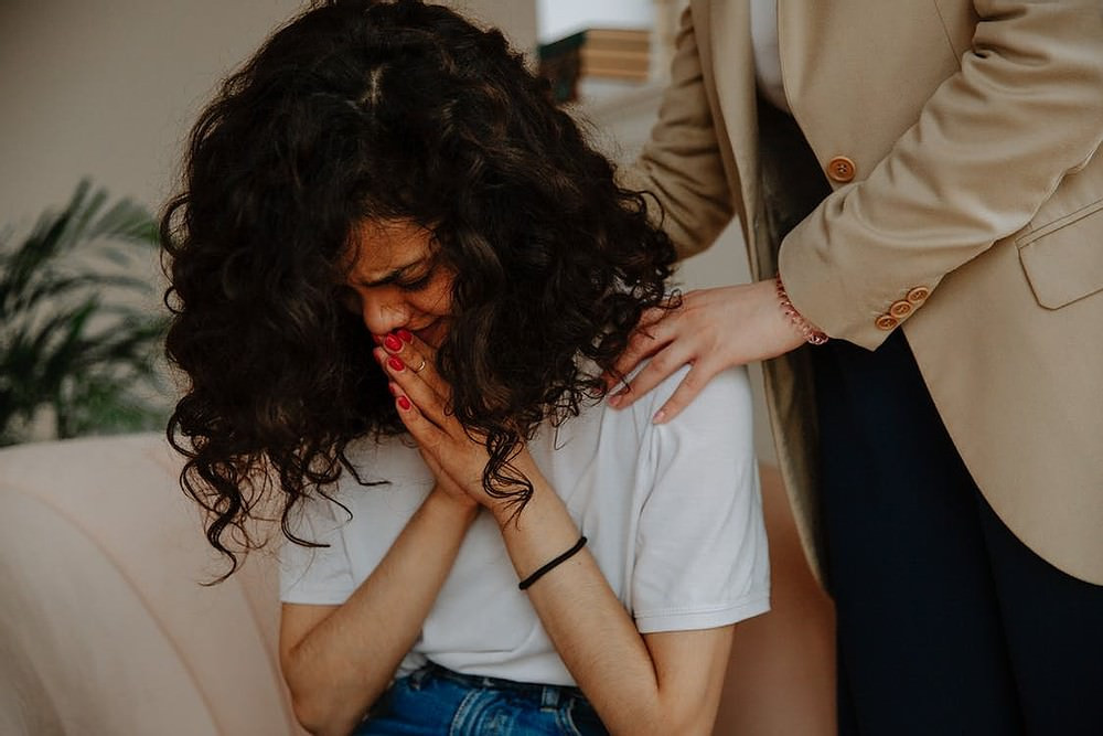 Desperate BAME woman with hands together.