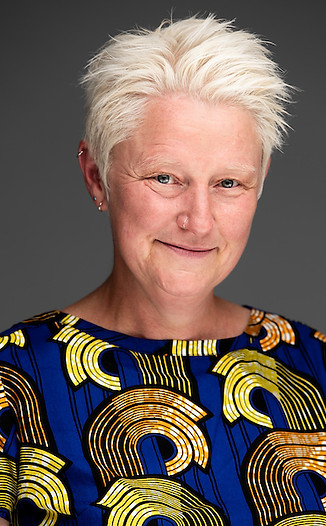 woman with grey hair smiling wearing a blue and yellow print top