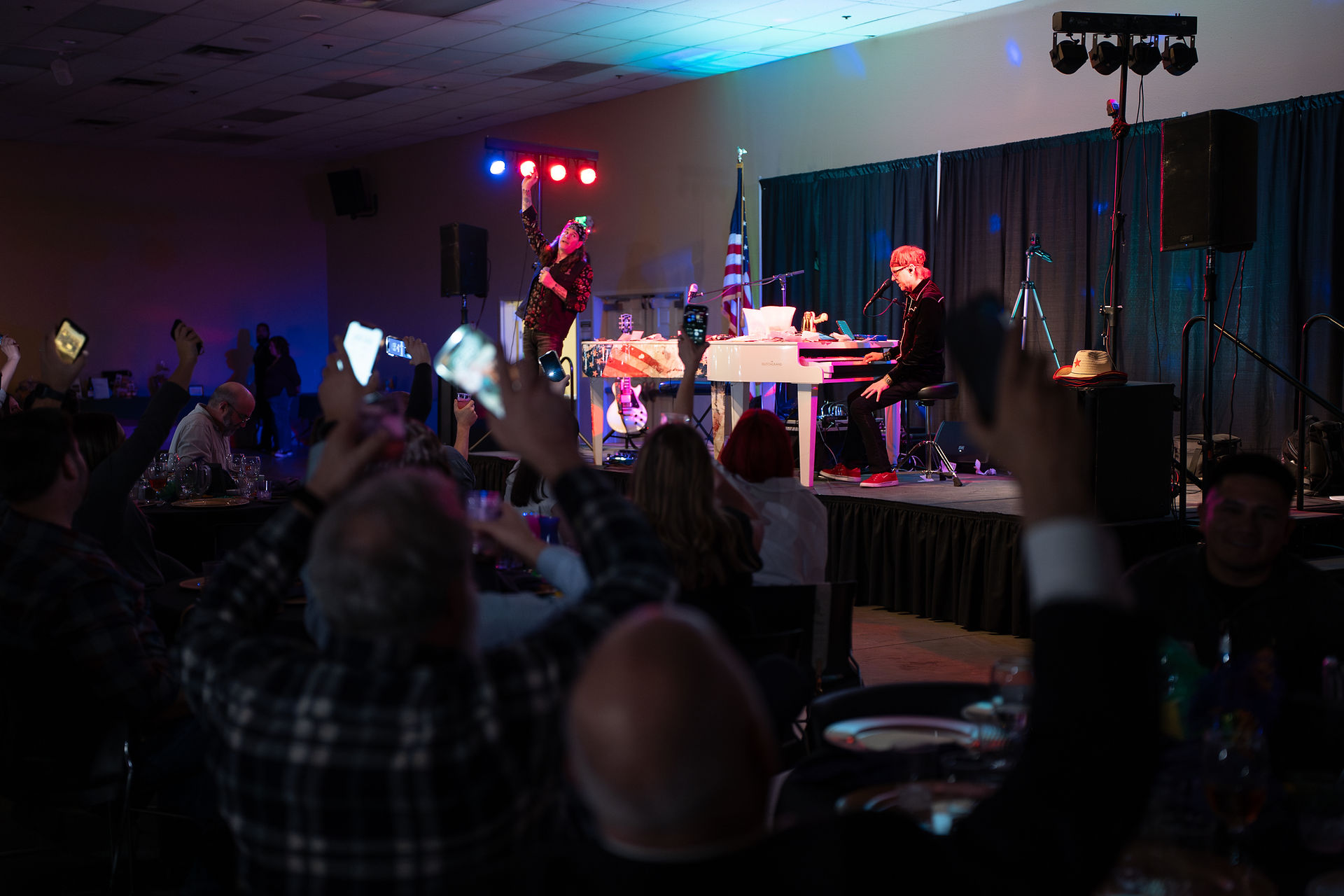 2 guys performing in front of crowd playing music.