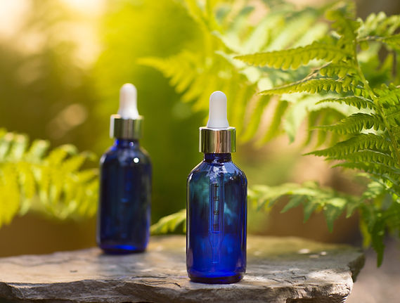 cosmetic products two blue glass bottles with oil on the roots of the tree against the bac