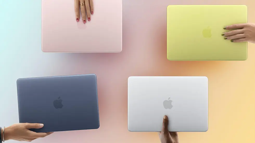 Four hands hold colorful laptops—pink, yellow, blue, silver—against a soft gradient background. Visible Apple logos, nails painted.