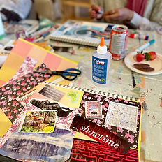 Close-up of a handmade collage in progress with paper, scissors, glue and art materials on the workshop table.