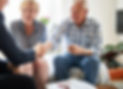 elderly couple sitting in a living room shaking hands with a business woman