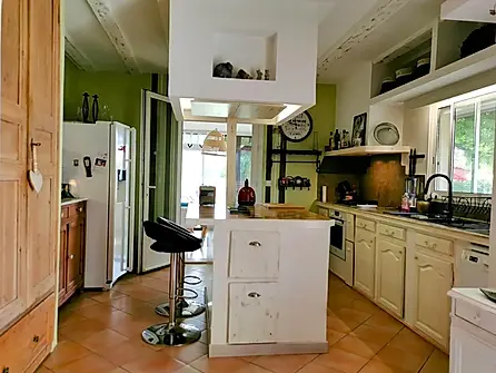 Cuisine équipée avec îlot central, électroménager moderne et ambiance chaleureuse