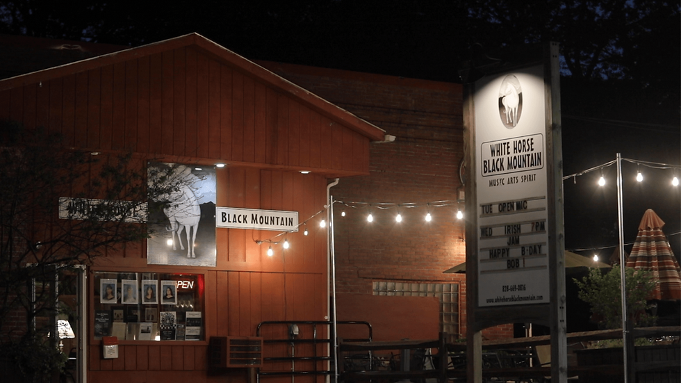Exterior view of White Horse Black Mountain at night, with string lights and venue sign at 105 Montreat Rd, Black Mountain, NC.