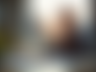 Junge, optimistische Person sitzt an einem modernen Schreibtisch in einer hellen Wohnung und plant Finanzen. Im Vordergrund liegen ein Schweizer Franken und Skizzen, im Hintergrund majestätische Schweizer Berge.