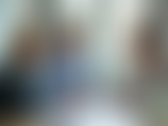 Professionelles Beratungsgespräch im modernen Büro zwischen einer Beraterin und einem Paar, die an einem Schreibtisch mit Dokumenten und Laptop sitzen.