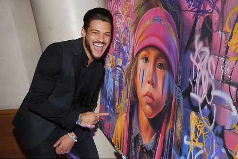 Rayane Bensetti pose aux côtés du tableau Native Indian Chef de Vincent Bardou lors du Grand Dîner organisé par Jules Durand et Noam Smadja. Découvrez l’univers street art et pop de l’artiste sur sa galerie d’art en ligne officielle.