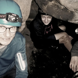 Group exploring a narrow cave passage during a Saxon Switzerland cave tour with guide