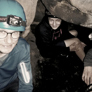 Group exploring a narrow cave passage during a Saxon Switzerland cave tour with guide